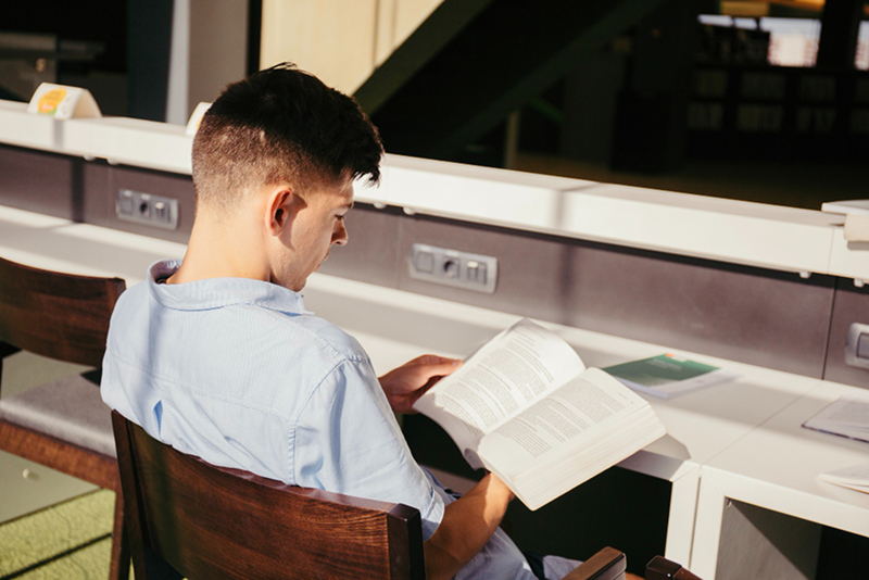 student reading textbook library desk morning light using free online doc translator